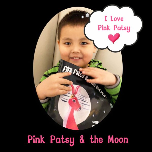 pink patsy and the moon x Young child smiling while holding a copy of Pink Patsy and the Moon.