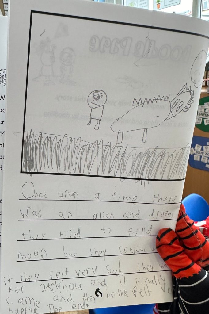 A child’s story page about an alien and a dragon looking for the moon, with a pencil drawing and handwritten story
