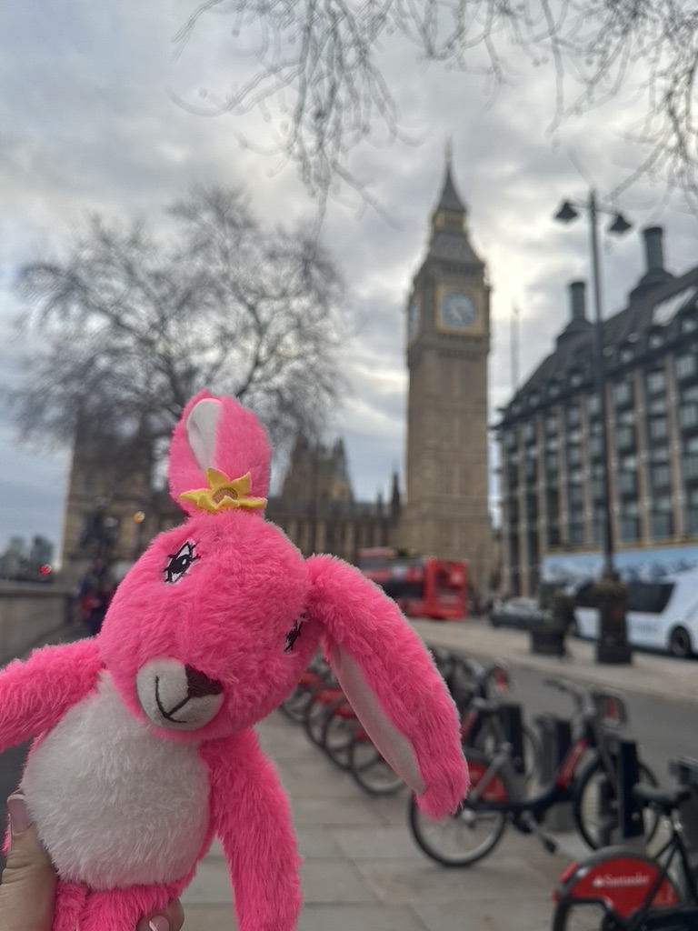 Pink Patsy in front of Big Ben and the Houses of Parliament in London, with a red double-decker bus